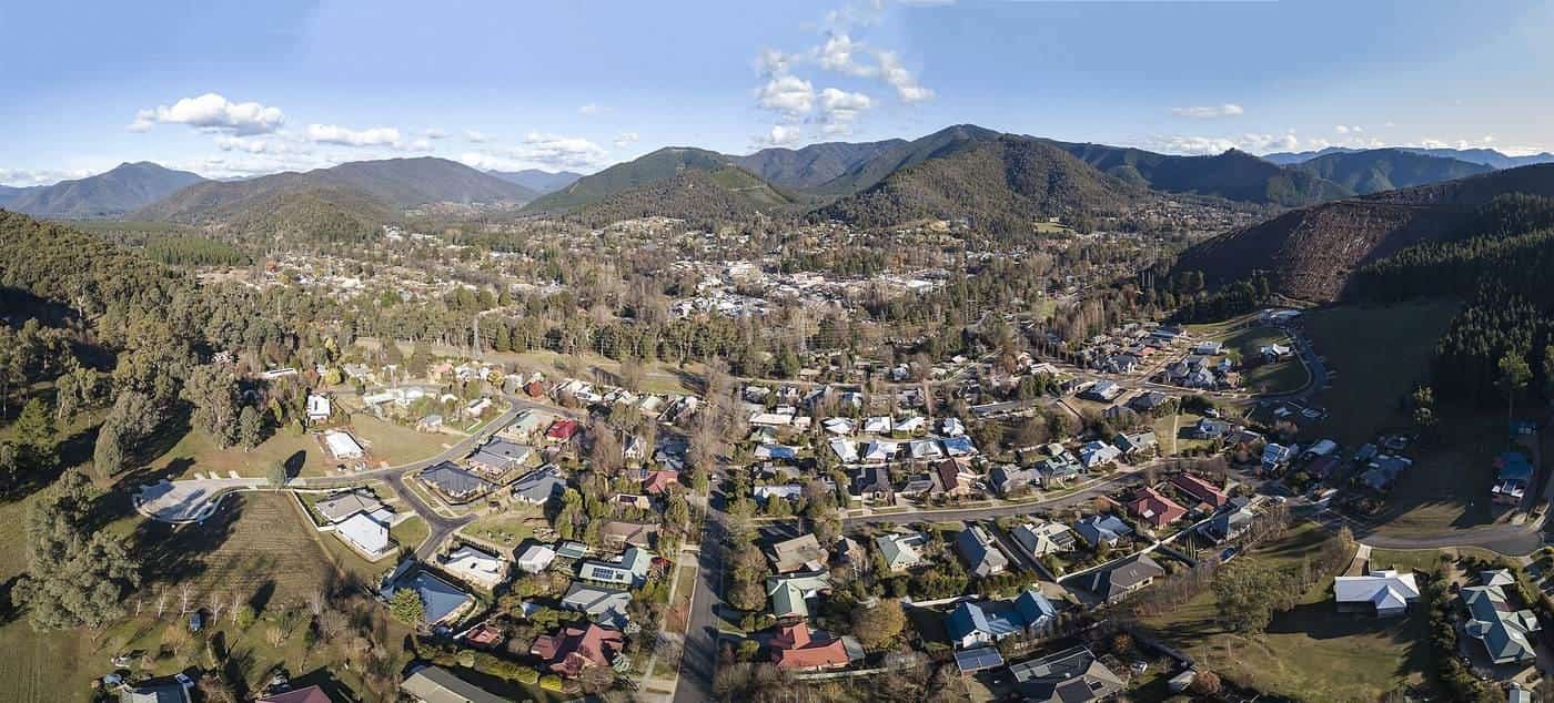 Aerial panorama of Bright, Victoria, in a green valley at the foot of forested mountains